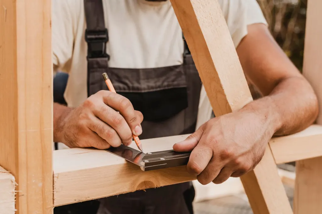 Montador midiendo y marcando un listón de madera